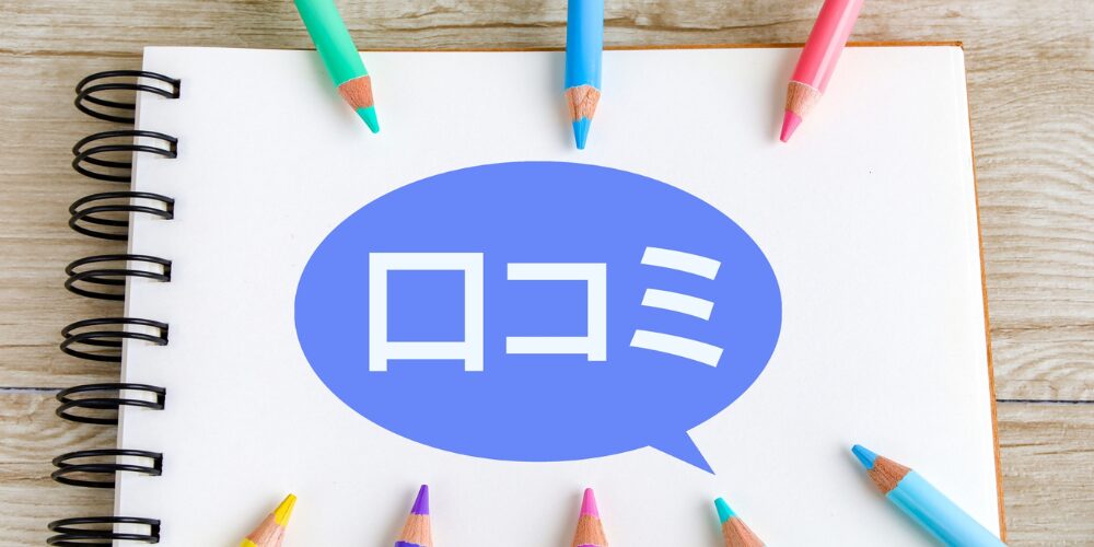 スパイラルノートの紙面中央に青い吹き出しがあり、その中に白文字で『口コミ』と書かれている。周囲にはカラフルな色鉛筆が円形に並んでいるイメージ
