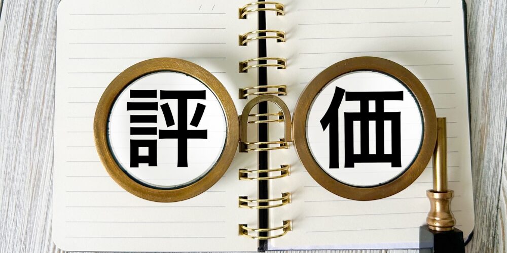 リング式ノートを開き、その上に二つの丸いルーペ越しに黒字で『評』と『価』の文字が並ぶ写真