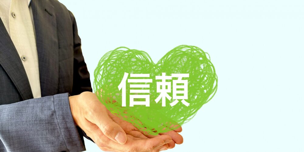 手のひらに乗った緑色のハートと「信頼」の文字手のひらに乗った緑色のハートと「信頼」の文字