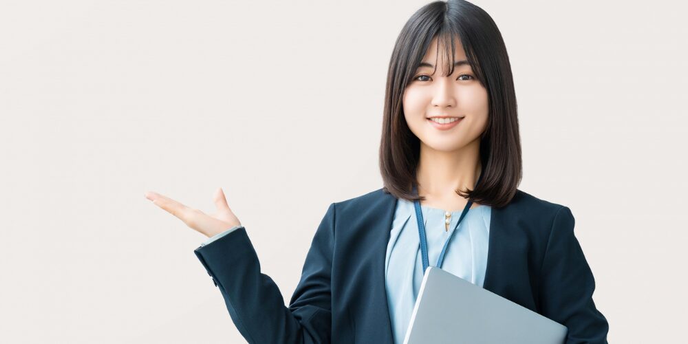 タブレットを抱え片手で示す女性スタッフの写真