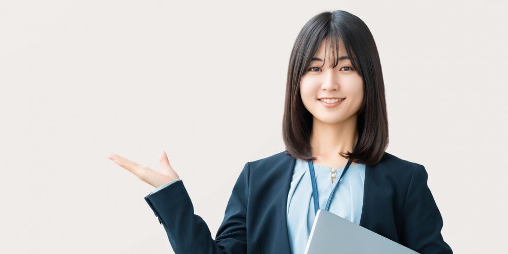 ノートパソコンを持ち案内する女性スタッフ